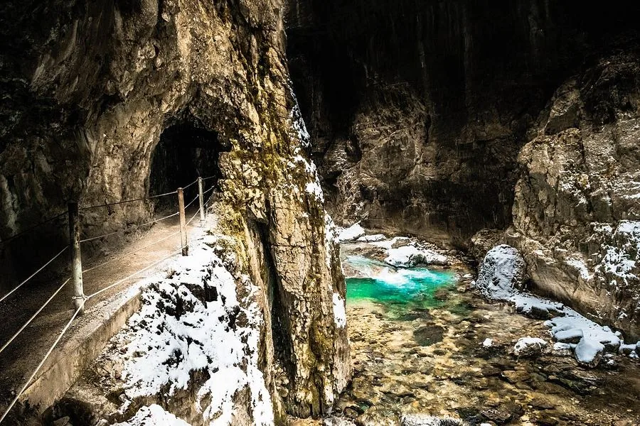 L'ingresso di un tunnel che si apre su una pozza turchese all'interno della gola