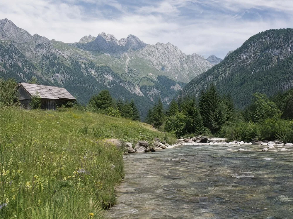 Un prato alpino accanto a un fiume limpido lungo il percorso di accesso